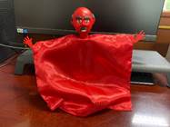 A red cloth with a face and hands  Description automatically generated